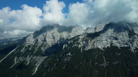 Side drone flight past rocky mountain peak and forest-covered slopes Stock Footage 314206672