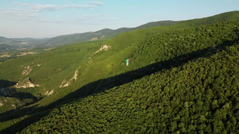 Side drone shot right to left of paraglider over Ozren Mountain cliffs, Serbia Stock Footage 328634191