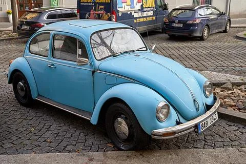 Side high angle view of vintage light blue Volkswagen VW Beetle car parked on Stock Photos