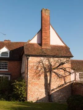 Side of house with small brown bare tree outside garden Stock Photos