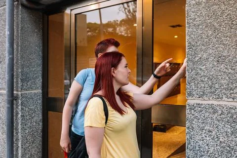 Side image of two young friends, ringing the doorbell of their friend's house Stock Photos