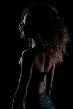 Side lit brunette girl with long curly hair, silhouette studio portrait on da Stock Photos