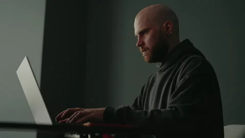 Side low-angle view of young bald programmer with ginger beard and ear piercing Stock Footage 305505410