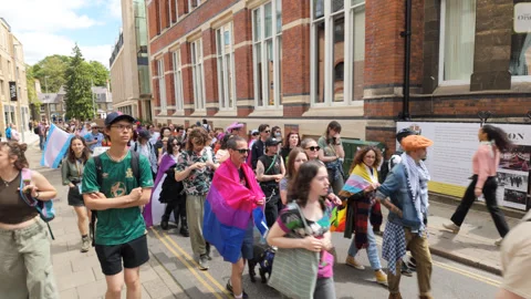From the side of the march at Cambridge Pride walking marchers pass Stock Footage 338016142