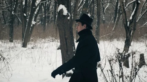 Side medium plan shot: A man in a black cloak and hat walks in the park. 60fps 動画素材 102170262