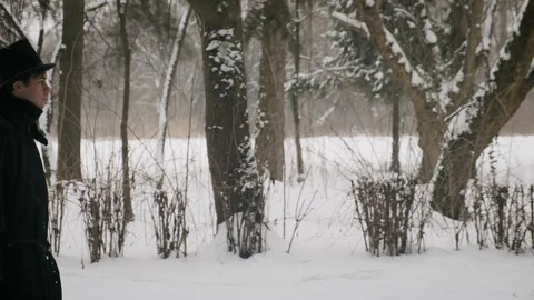Side medium plan shot: A man in a black cloak and hat walks in the park. 60fps Stock Footage 102188378
