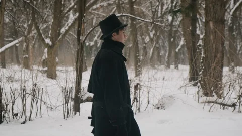 Side medium plan shot: A man in a black cloak and hat walks in the park. 60fps 動画素材 102188816