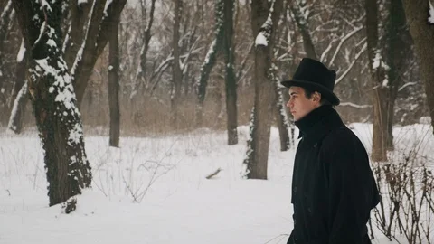 Side medium plan shot: A man in a black cloak and hat walks in the park. 60fps Stockbeeldmateriaal 102189687