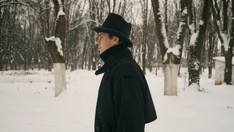 Side medium plan shot: A man in a black cloak and hat walks in the park. 60fps Stockbeeldmateriaal 102194255