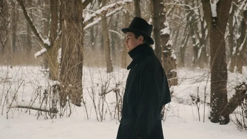 Side medium plan shot: A man in a black cloak and hat walks in the park. 60fps Stockbeeldmateriaal 102198170
