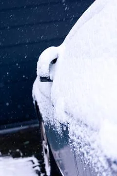 A side mirror and side window of a car at the driver side covered in white sn Stock Photos