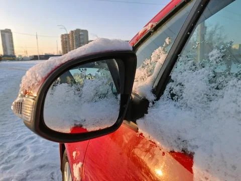 The side mirror and window of the red car is covered with fresh snow Stock Photos
