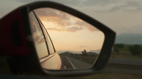 Side mirror of car reflecting orange sunset and cloudy sky Stock Footage 185193378
