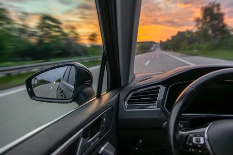 Side mirror on highway drive. Sunset travel and automotive content. Fotos de archivo