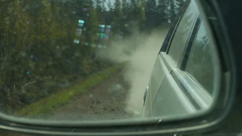 Side mirror reveals engulfing dust cloud close to vehicle, courieronroute Stock Footage 333909536