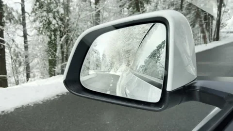 Side mirror view of a electric car driving on a winter road with snow scenery Stock Footage 225682996