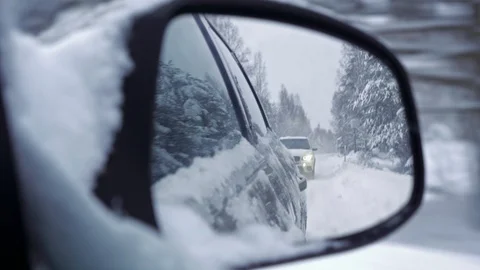 Side mirror view of following car in snowy weather Stock Footage 102926826