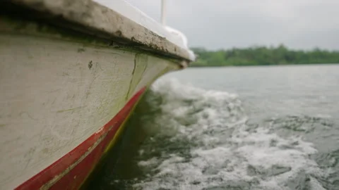 Side of moving boat cuts through water, creating wake on river. Close up view of Stock Footage 265609995