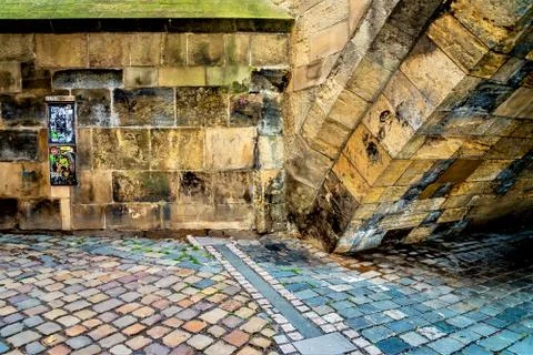 Side of an old arched structure made of concrete bricks on cobblestone street Foto stock
