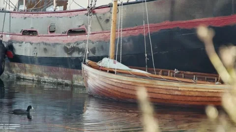 Side of an old moored ship with a boat tied Vídeos de archivo 258553514