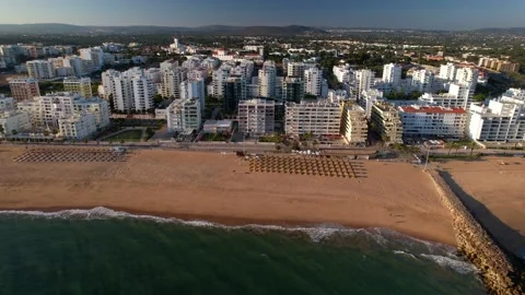 Side panning aerial view of beach, boardwalk and buildings in Quarteira, Algarve Stock Footage 195940566