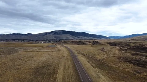 Side panning shot over empty highway surrounded by grass fields with rolling Stock Footage 125050657