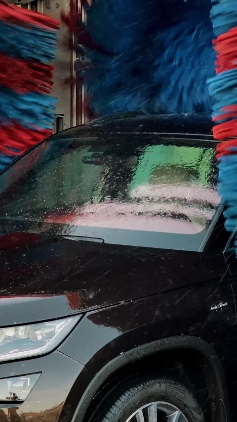 Side part of car being processed by blue rotating brushes of automatic wash. Stock Footage 324928398