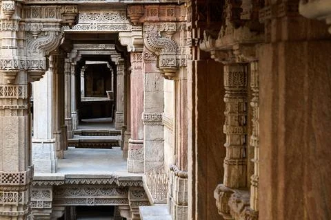 Side perspective of decorated stone pillars and carved friezes along a walkwa Photos
