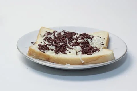Side perspective of white bread with grated cheese and chocolate sprinkles .. Stock Photos