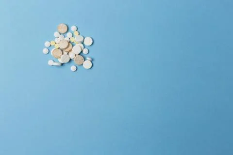 Side placed bunch of tablets various kinds and sizes lay on a light blue surface 스톡 사진