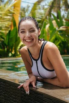 On the side of the pool leaned out of it cheerfully laughing girl against the Stock Photos