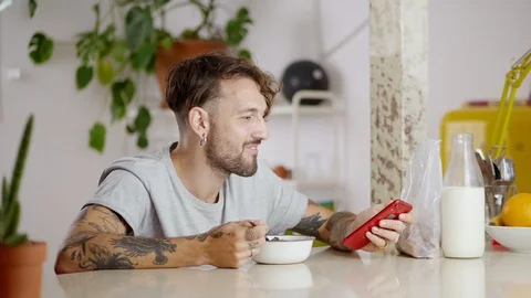 Side portrait of engaging guy chewing morning flakes using gadget to stay Stock Footage 108795742