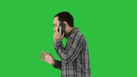 Side portrait of a happy student walking and talking on mobile phone on a Green Vídeos de archivo 99752799