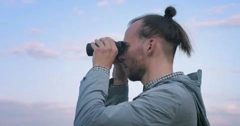 Side portrait of hipster bearded man looking into binoculars afar handheld Stock Footage 134759849