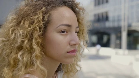 Side portrait of a thoughtful young Hispanic woman sitting alone in the city  Stock Footage 80657089