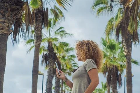 Side portrait of tourist using mobile phone in outdoor with palms street ro.. Stock-Fotos