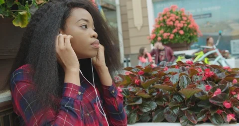 Side portrait of the yo ung pretty african putting o nthe earphones and enjoying Stock Footage 89905377