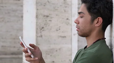 Side portrait of a young attractive man using cell phone in the city Stock Footage 66679938