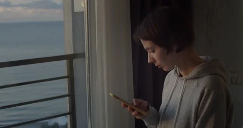 Side portrait of young millennial girl using smartphone reading news. Attractive Stock Footage 168661053