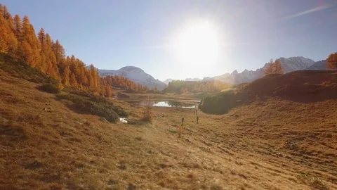 Side POV walking on fall field path near lake with sun and snowy mounts.Sunny 動画素材 80088334