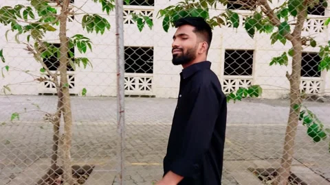 Side profile of a bearded man in black attire walking by a tree with a text.. Stock Footage 262248227