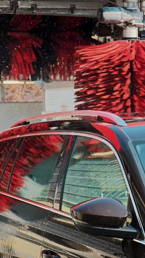 Side profile black car under red brushes in automatic wash Stock Footage 343794108