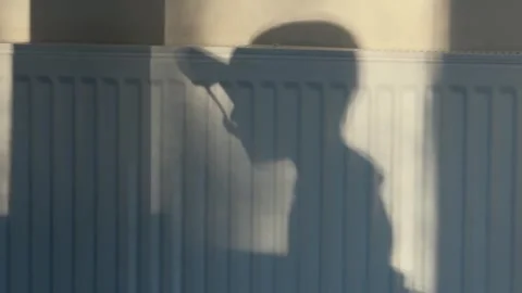 Side Profile of Boy's Mealtime Shadow on Wall by Radiator Stock Footage 348087635