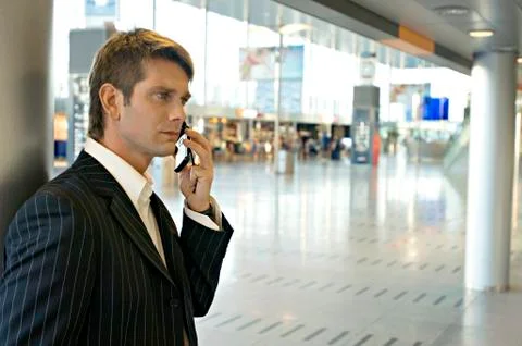 Side profile of a businessman talking on a mobile phone at an airport Stock Photos