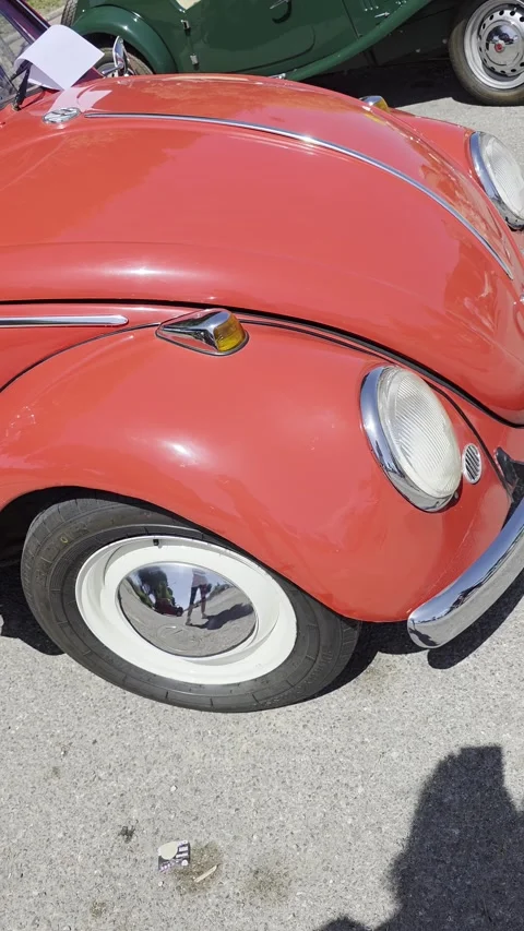 Side profile of a classic vintage red Volkswagen Beetle, starting from the f Stock Footage 339245408