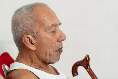 Side profile of elderly man sitting with cane reflecting aging and limited .. Stockfoto's