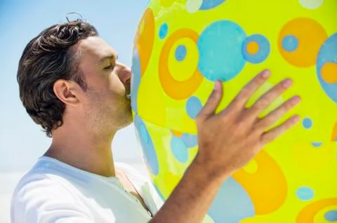 Side profile of a man blowing beach ball Stock Photos