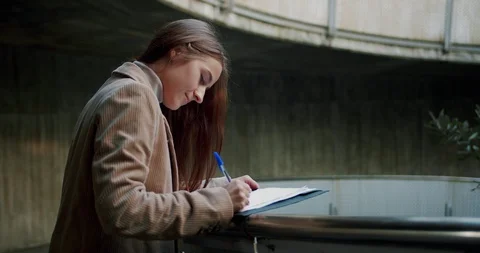 Side profile shot of diligent Caucasian female making notes on document using Stock Footage 120747241