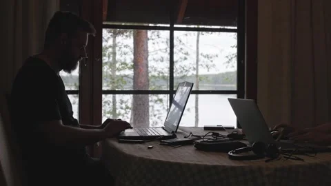 A side profile silhouette of a man working on a laptop. Horizontal. Stock Footage 341361339