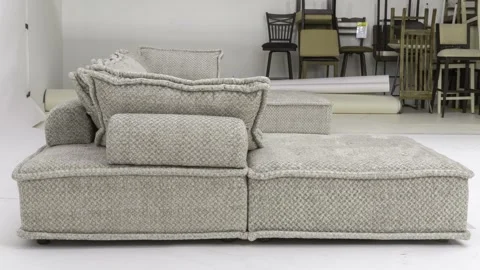 Side profile of soft modern wool sectional with stacked dining chairs in Stock Footage 279227680
